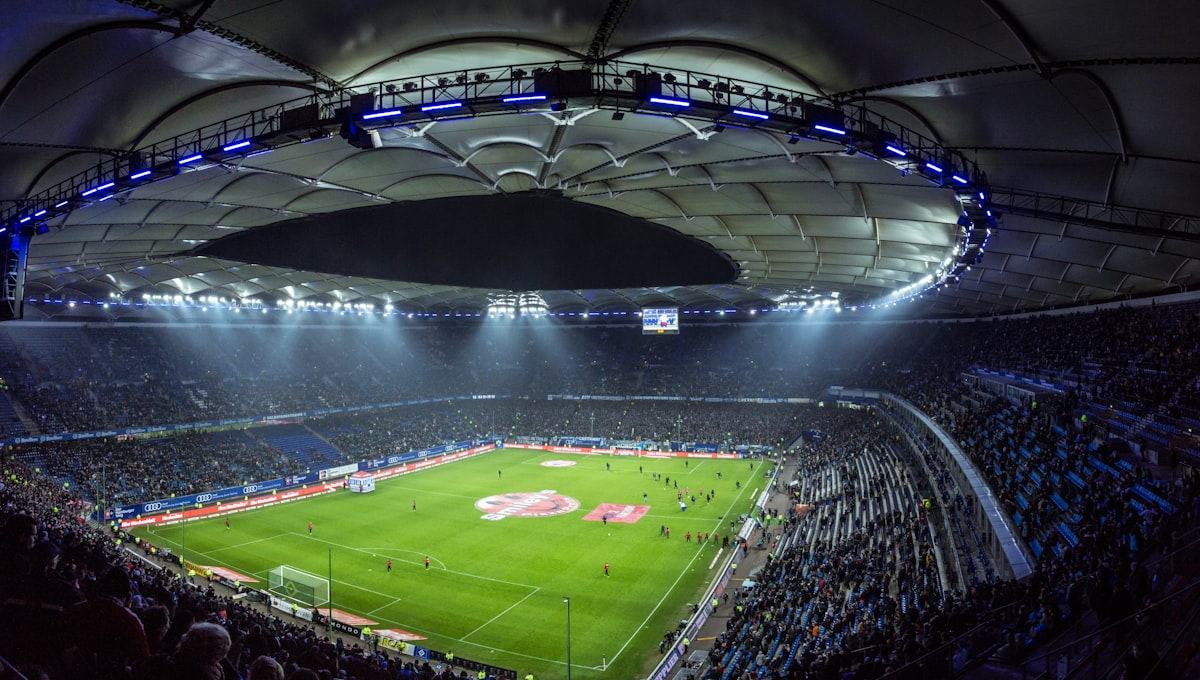 Stadion sepak bola dengan lampu sorot menyala pada malam hari